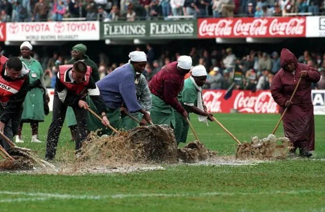 Men and Women clear water off the pitch