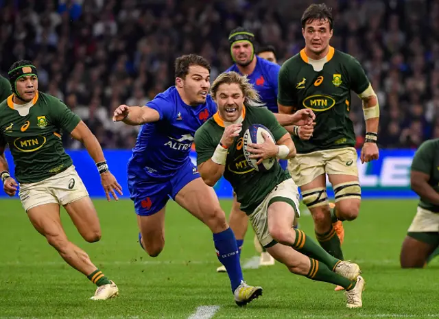 Faf de Klerk runs wiht the ball as Antoine Dupont tackles him