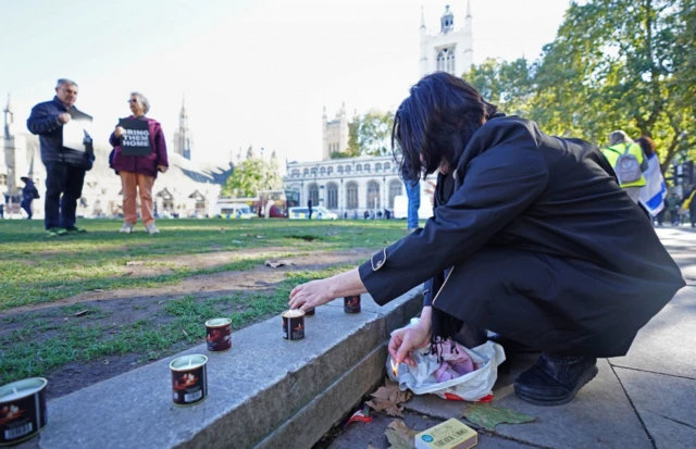 A woman lights a candle a vigil at Parliament Square in London, for victims and hostages of the Hamas attacks.