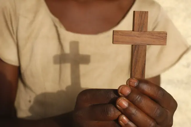 A young Christian holds a cross