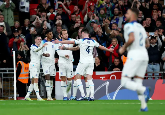 Players run to celebrate with Harry Kane after his second goal.