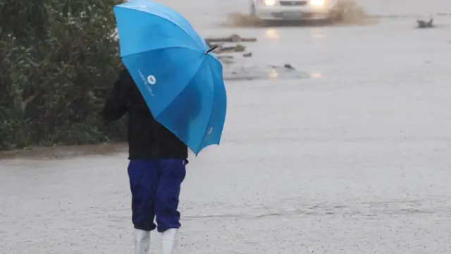 A person looks at a flooded road following heavy rains, in Grabouw, Western Cape, South Africa, September 25, 2023.