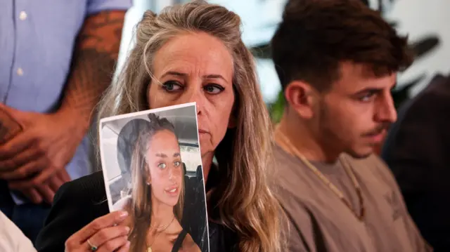 Keren Shem holds up a photo of her daughter, Maya, an Israeli-French woman being held hostage by Hamas militants in Gaza (17 October 2023)