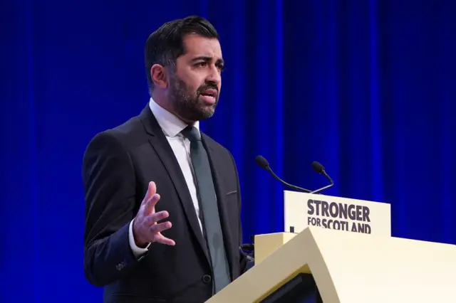 Humza Yousaf speaking at a podium