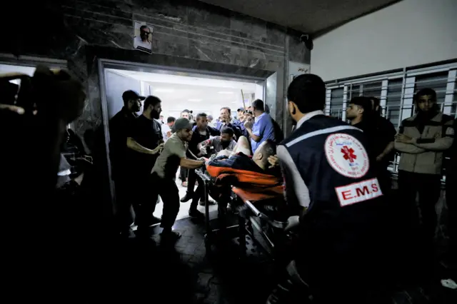 An injured man is taken into the nearby Shifa hospital following the strike