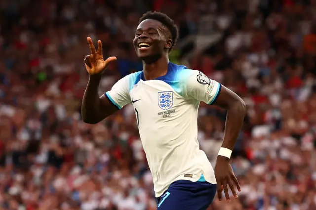 Saka holds up three fingers to celebrate scoring his hat-trick.