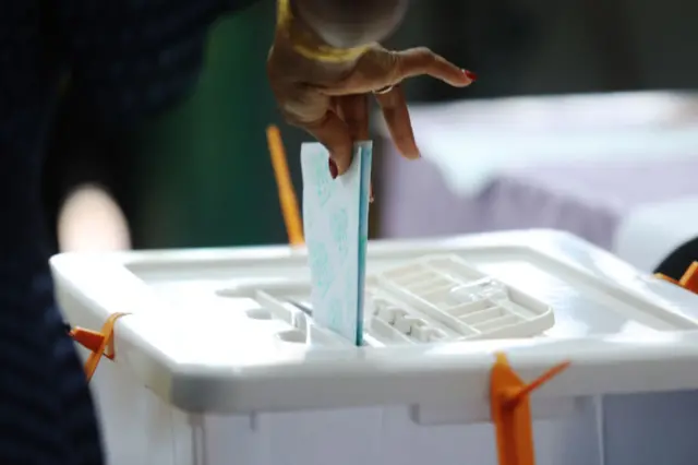 A voter puts their ballot in the box.