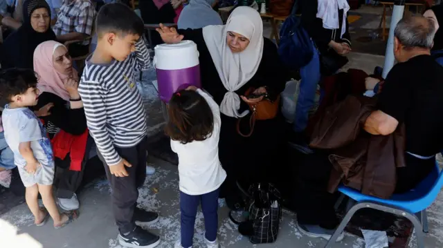 A young girl gets water from a vat