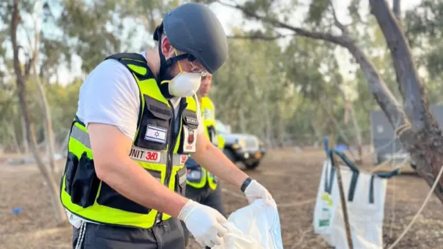 A man wears protective gear and holds a plastic bag