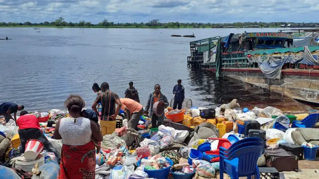 People stand among the belongings of the passengers of the boat capsized on the Congo river late on Friday in Mbandaka, Democratic Republic of Congo, October 16, 2023.