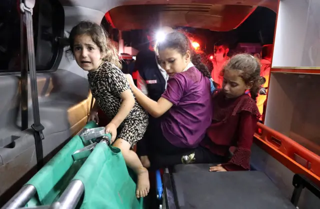 Children sit in the back of an ambulance at Shifa Hospital