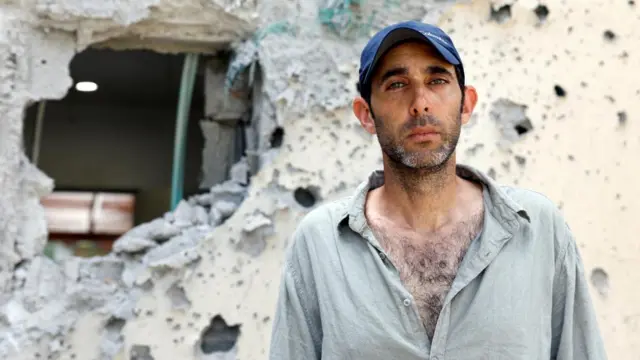 Roman stands in front of a ruined wall