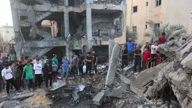 People gather as Palestinians work to remove casualties from under the rubble of a house destroyed by Israeli strikes, in Khan Younis in the southern Gaza Strip October 17, 2023.