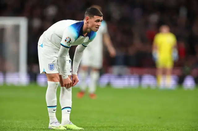 Foden pulls up his socks after getting back to his feet.