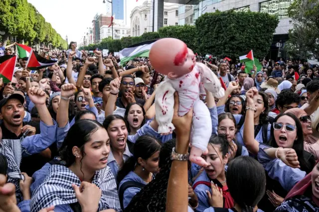 Tunisian protesters holds up a doll as several thousand demonstrators, mostly young people, show their support for Palestine by marching through Avenue Habib Bourguiba and continuing their demonstration in front of the French Embassy on October 18, 2023 in Tu