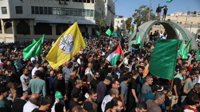 Dozens of protesters waving flags in the West Bank