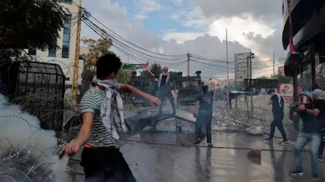 People clash with security forces during a protest near the U.S. embassy in Awkar