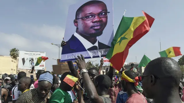 Protesters hold flags of the Senegal and a portrait of the opponent and Mayor of Ziguinchor Ousmane Sonko as they attend a rally of the Senegalese opposition in Dakar - June 2022