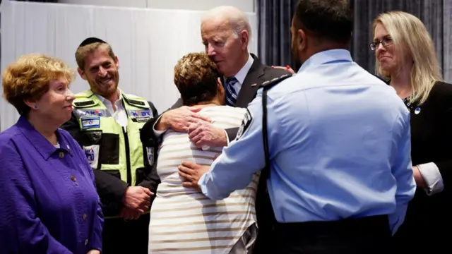 President Biden embraces a woman while others look on