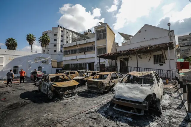 Burnt out cars in front of a partially damaged building at the scene at Al Ahli hospital in Gaza