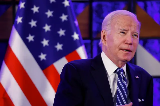 Joe Biden speaks in front of an American flag