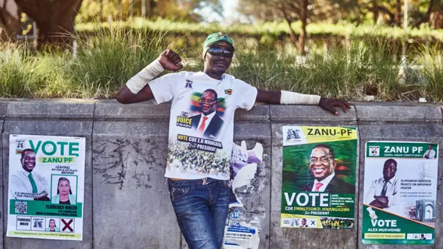 A Zanu-PF supporter next to Zanu-PF electoral posters in Gweru, Zimbabwe - July 2023