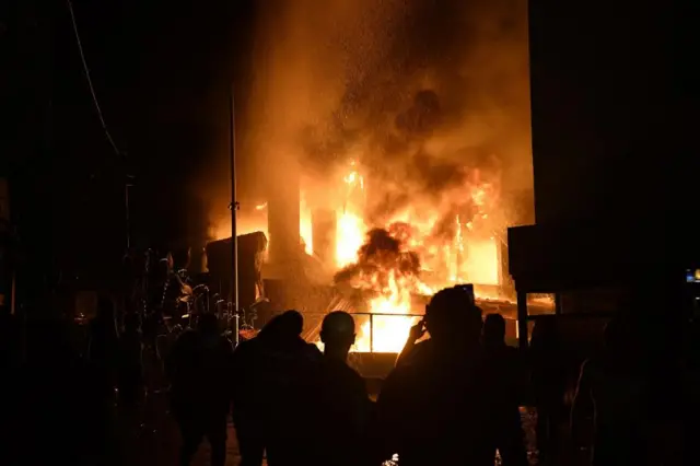 People stand in front of fire that erupted outside the US embassy in Beirut