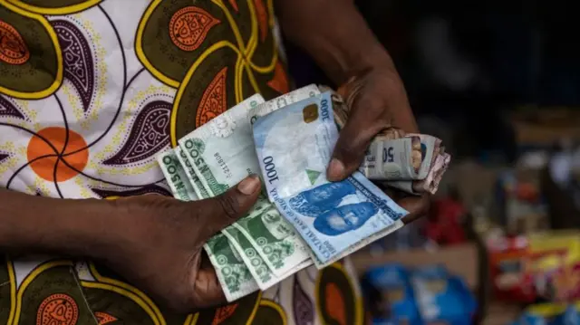 A vendor shows old and newly introduced Nigerian Naira banknotes in a market in Lagos on February 2023