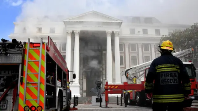 A firefighter looks at the smoke rising after a fire broke out in the parliament in Cape Town, South Africa - 2 January 2022