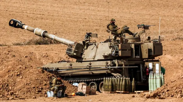 An Israeli soldier sits on a self-propelled howitzer near Israel's border with the Gaza Strip