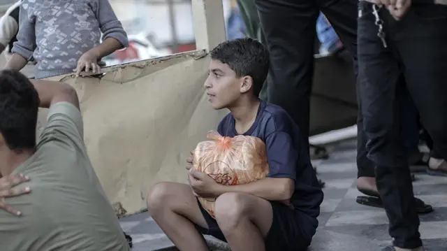 A child holds a ration of bread as Khan Yunis camp residents queue outside a bakery, in the southern Gaza Strip, 17 October 2023.