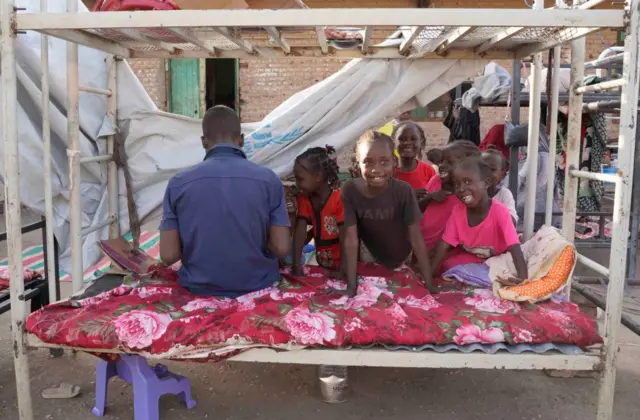 People on an a bed at Hasahisa secondary school, El Gazira state, Sudan - July 2023