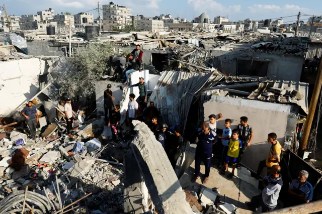 Palestinians gather around the debris of a house destroyed in an Israeli strike in Khan Younis