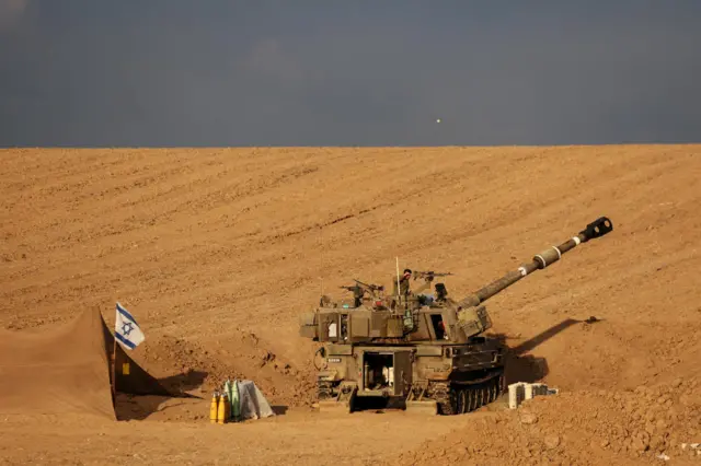 An Israeli soldier shades his eyes from the sun as he stands on a self-propelled howitzer near Israel's border with the Gaza Strip, in southern Israel