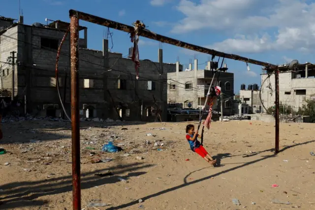 A child swings at the site of an Israeli strike in Gaza