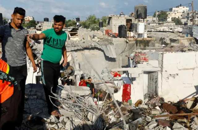 Men search for bodies under the rubble of a house destroyed by an Israeli strike