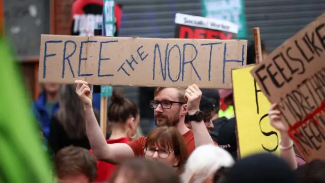 A man holds a sign reading 'Free the north' at a protest in Manchester, 1 October 2023