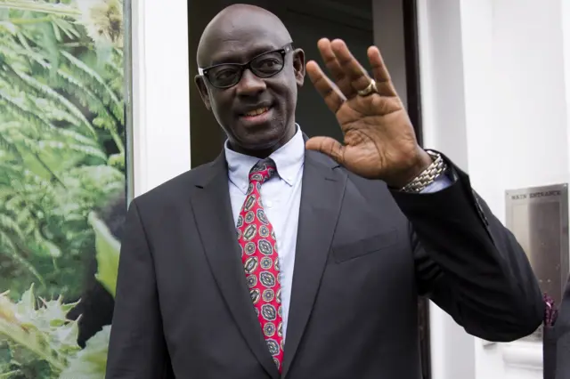 Rwanda Justice Minister Busingye Johnston waves as he leaves the Rwanda High Commission in London after a court in Britain