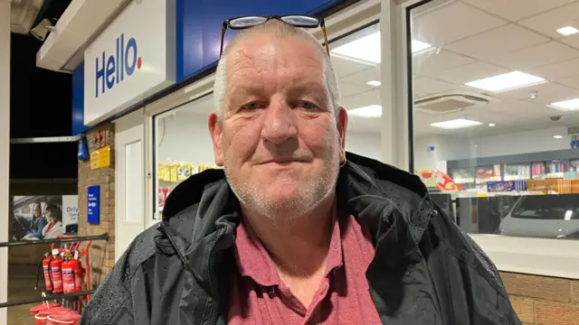 A male constituent in flitwick in Bedfordshire. He is in front of a petrol station.