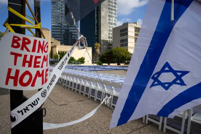 An Israeli flag hangs next to a sign reading "Bring them home"