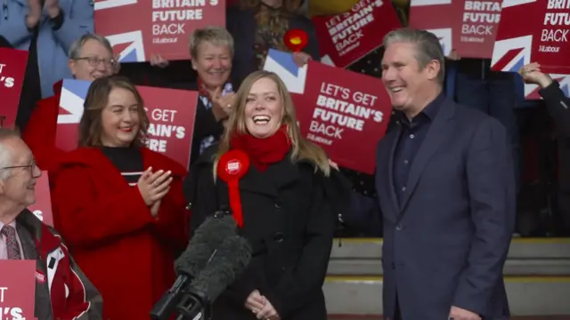 Starmer and new MP Sarah Edwards smiling and surrounded by party members with placards