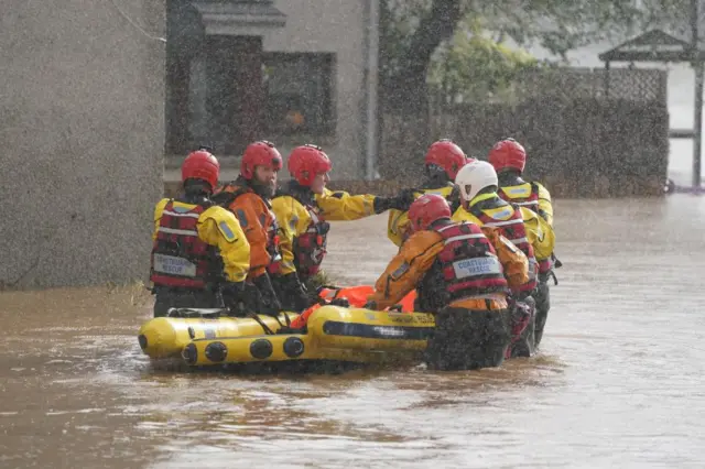 Rescuers push boat through a flood