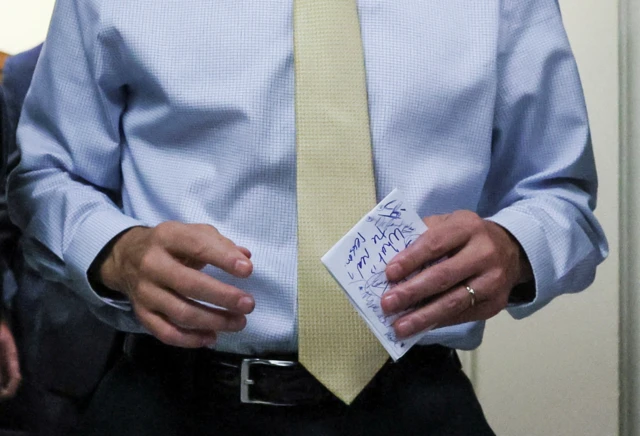 Jim Jordan seen carrying a piece of paper with the words "What is the real reason" written on