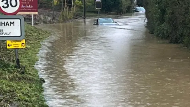 Cars left in the middle of a flooded road