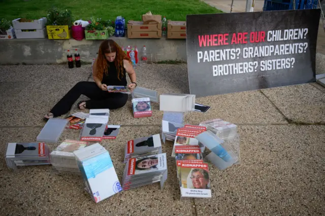 A woman sorts through missing posters for the 200 hostages