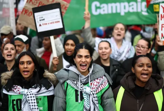 A group of protesters with three women in the foreground chanting