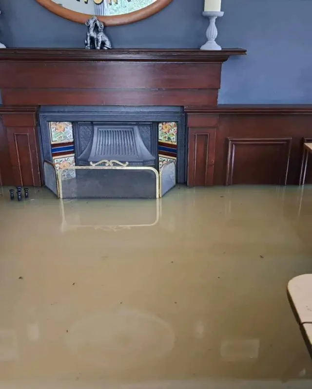 Inside the pub is flooded, dirty water and it is halfway up a fireplace.