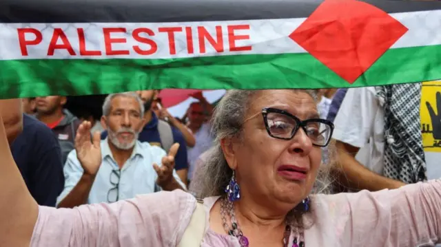 A woman cries while carrying a Palestinian flag