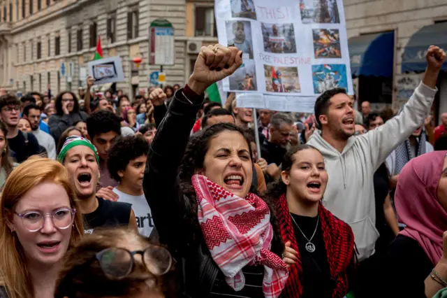 A crowd of protesters holding flags and signs in support of Palestine in Rome