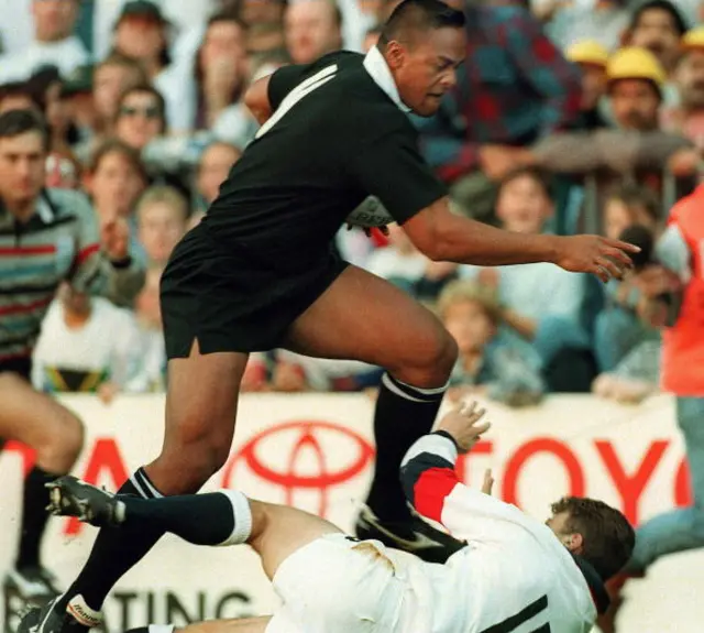 New Zealand winger Jonah Lomu runs through England's fullback Mike Catt